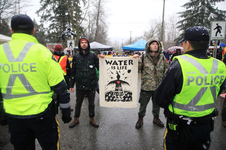Two protesters face police officers outside the entrance of Kinder Morgan's tank farm in Burnaby in March.