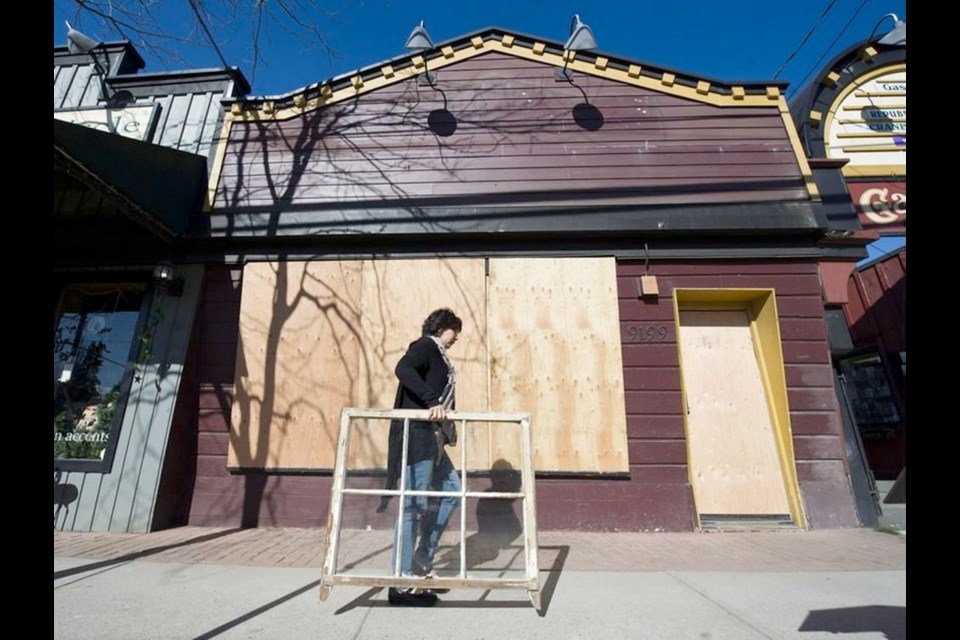 A woman walks past a boarded-up property on Glover Road owned by developer Eric Woodward in Fort Langley. He has six buildings boarded up on the town&Iacute;s main street, worrying people who rely on the tourist trade for their income.