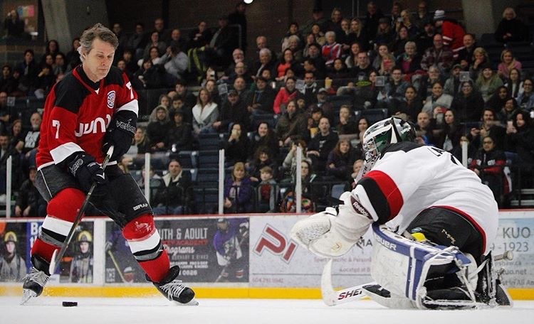 A helmet-less Jim Cuddy of Blue Rodeo brings goalie Grant Lawrence to his knees. Photo Kevin Light