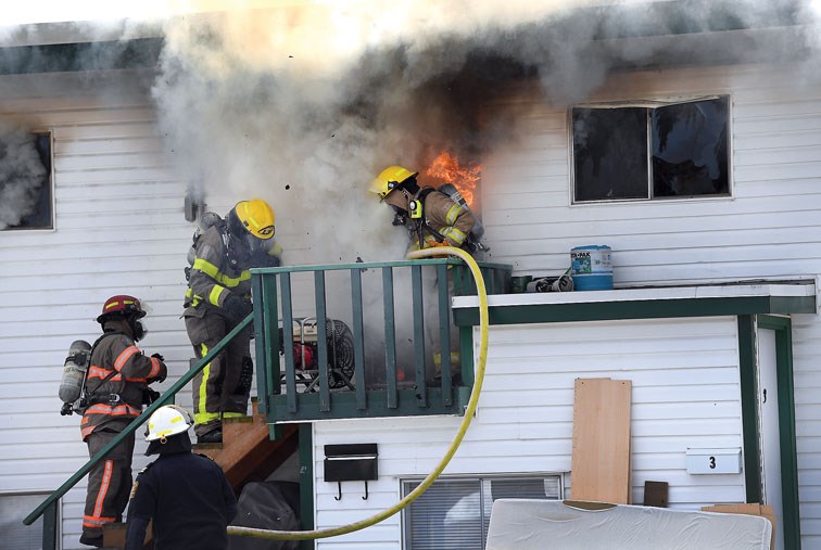 Flames burst out of a door as firefighters deal with a blaze midday Wednesday at a fourplex at Massey and Westwood. Citizen photo by Brent Braaten.