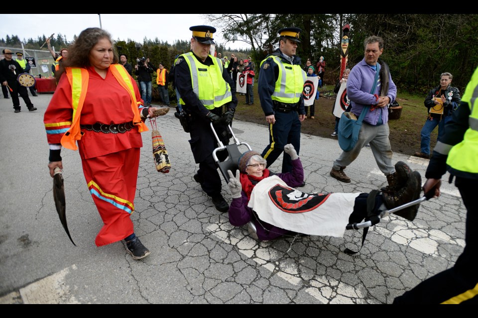 Protester Nan Gregory is carried away by Burnaby RCMP after protesting at the Trans Mountain terminal in Burnaby on Friday.