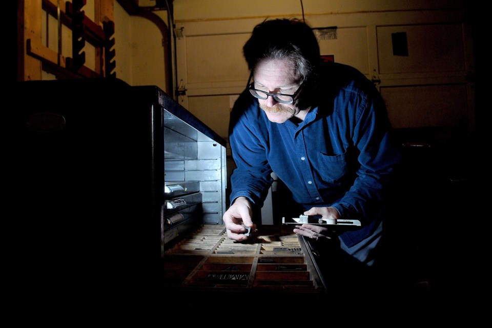 Markus Fahrner sorts through blocks of metal fonts he uses to create books and posters on his 1914 printing press in hisgarage.