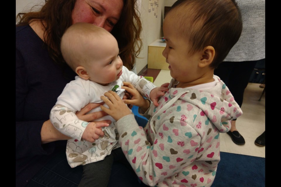 Nine-month-old Natalie and Walter Lee elementary Grade 1 student Kelsey Chen, who is blind, communicate through touch in a Roots of Empathy class. Photo submitted