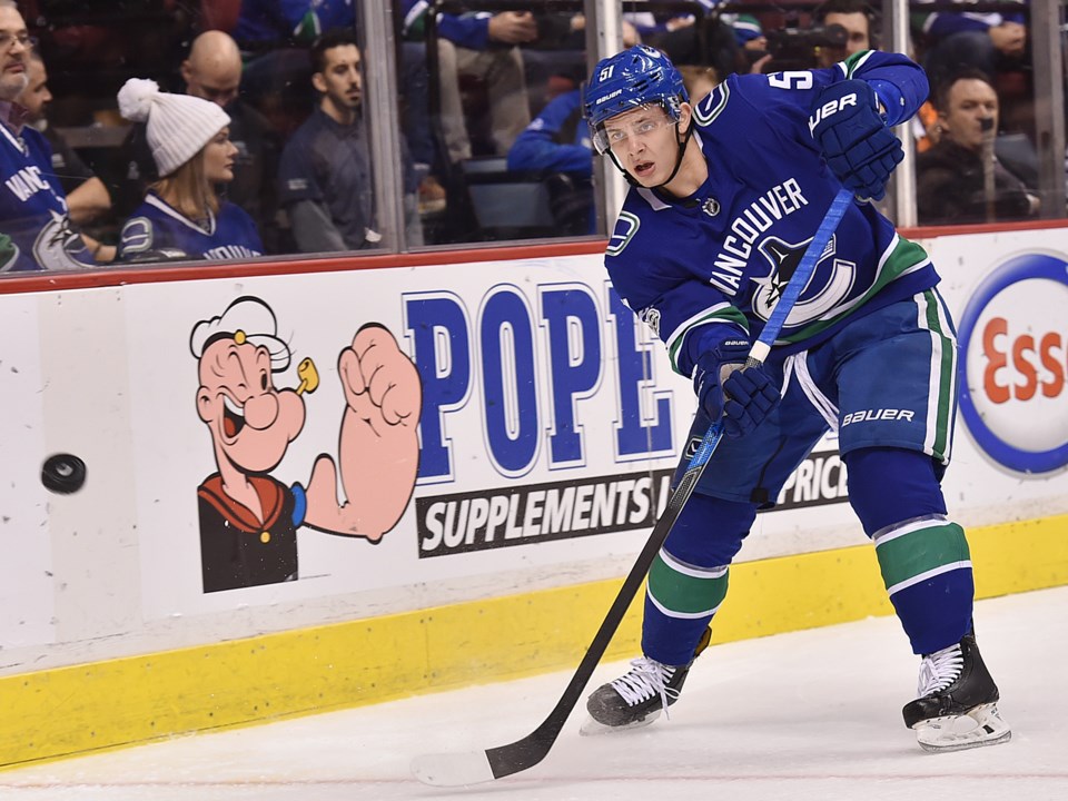 Troy Stecher chips the puck around the glass for the Vancouver Canucks