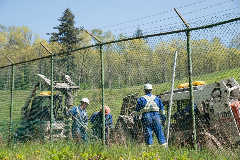 Workers install new fence posts surrounding the Burnaby B.C., Kinder Morgan location Thursday, April 26, 2018. THE CANADIAN PRESS/Jonathan Hayward
