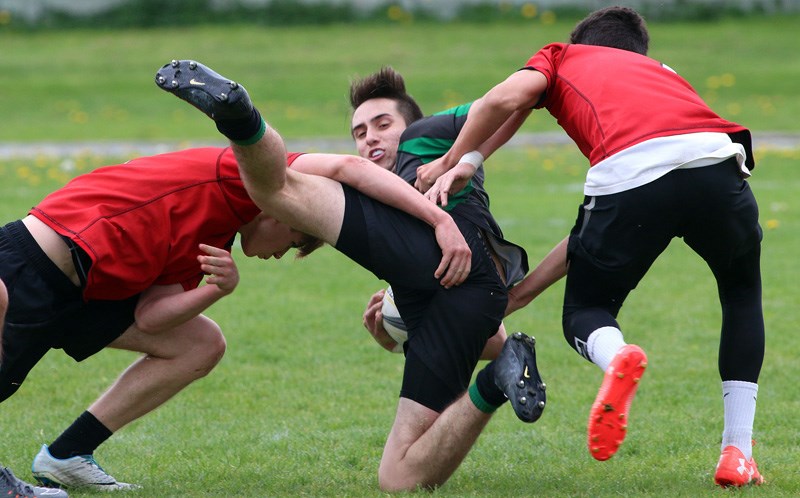 Riverside Rapids ball carrier Ethan Kelt is upended by Terry Fox Ravens defenders Trey Hayward and Ethan Elliot in the first half of their BC high school rugby match, Monday at Terry Fox secondary school. The Ravens defeated their crosstown rivals 34-0.