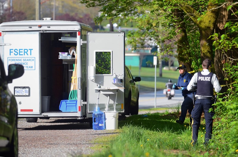 A forensic investigator emerges from a wooden area in Burnaby's Confederation Park, where partial human remains were discovered Tuesday morning.