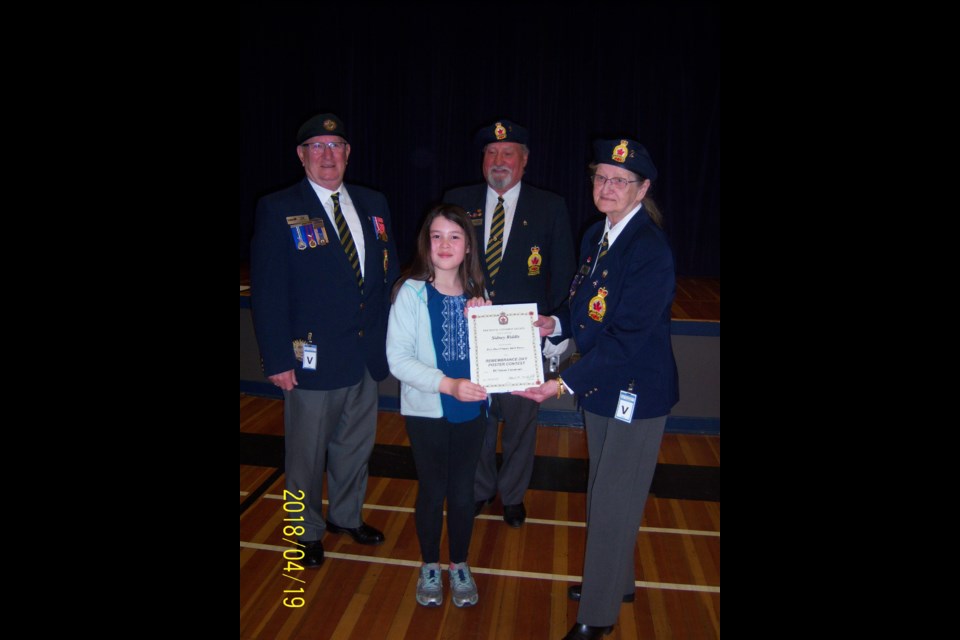 Royal Canadian Legion Branch 2 poppy chairman Pat Andre presents Richard McBride student Sidney Riddle with a provincial certificate for her winning entry in one of the Legion's poster contests, while president Clarence Thompson, centre, and service officer Terry Leith, left, look on. The first photo is of the winner of First place Sidney Riddle being presented with the Provincial certificate by Pat Andre.