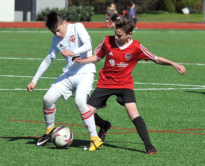 Burnaby District’s Jaden Edwards, left, guards the ball from a North Shore rival during the Coastal Cup semifinals. Burnaby blanked Surrey 4-0 in the final and now advances to the provincial cup tournament in July.