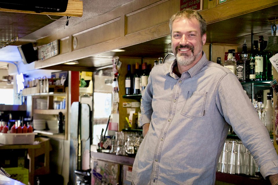 Glenn Cormier leans against the wooden bar that dates back to Expo '86.