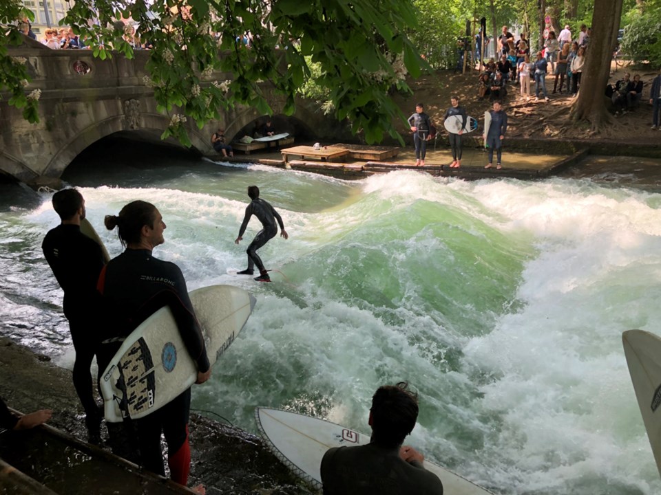 Surfers ride a human-made standing-wave at the Eisbach (German for