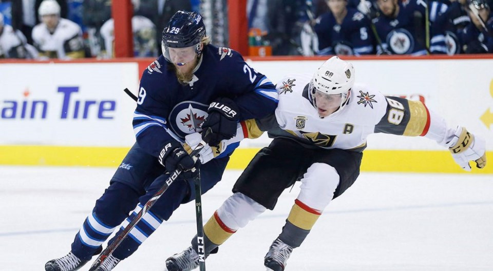 Nate Schmidt of the Vegas Golden Knights battles the Winnipeg Jets' Patrik Laine for the puck.