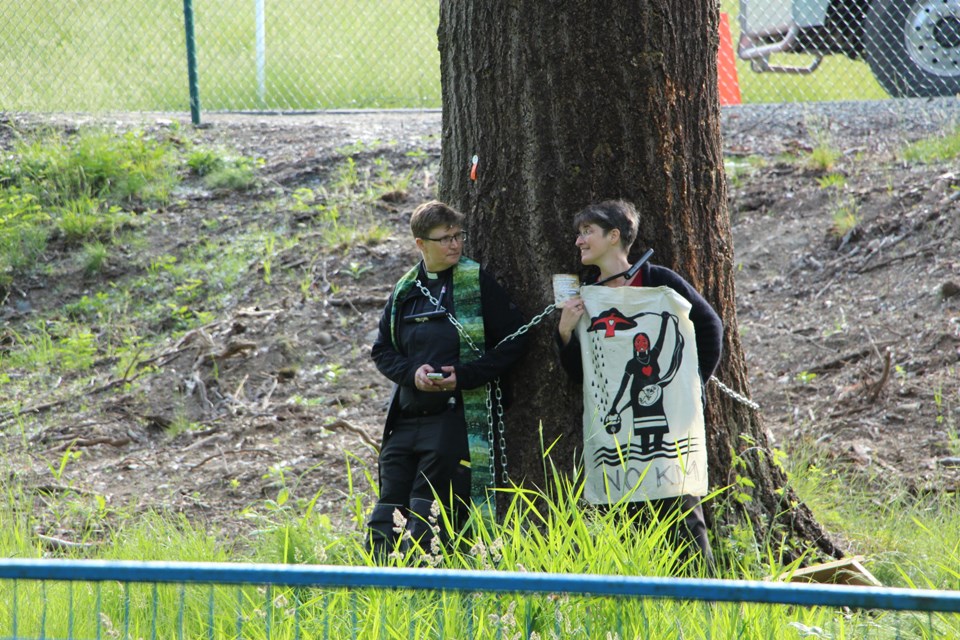 Anglican priest Laurel Dykstra (left) and parishoner Lini Hutchings chain themselves to a tree west of the Trans Mountain terminal on Burnaby mountain Friday (May 25) morning.