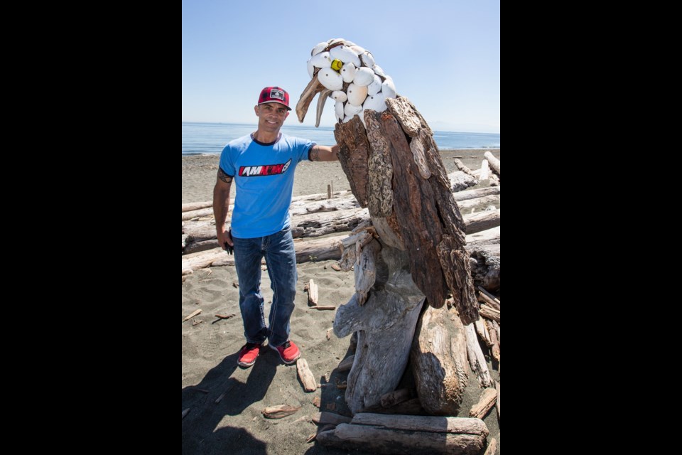 Paul Lewis at Esquimalt Lagoon with one of his creations: a driftwood bald eagle.