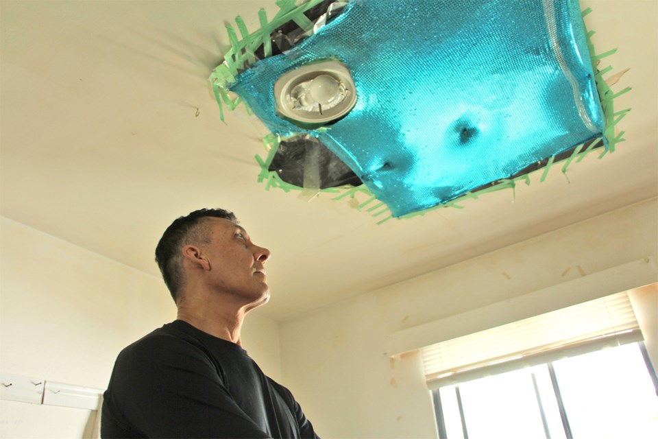 Tom Hassan Aravi looks at his bedoorm ceiling with covering he installed after it collapsed.