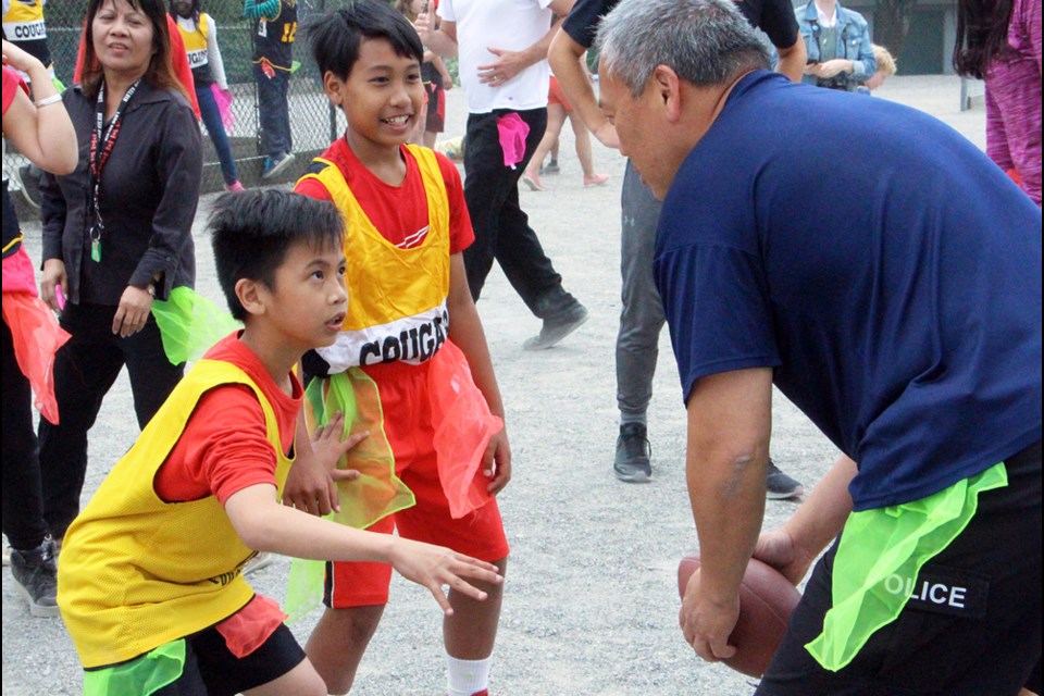 On the run: Lord Kelvin Grade 5 students Rolly Raymundo and Jailan Pagtakhan go head-to-head with New Westminster Police Const. Gerald Lau in last Wednesday’s students versus staff football game.