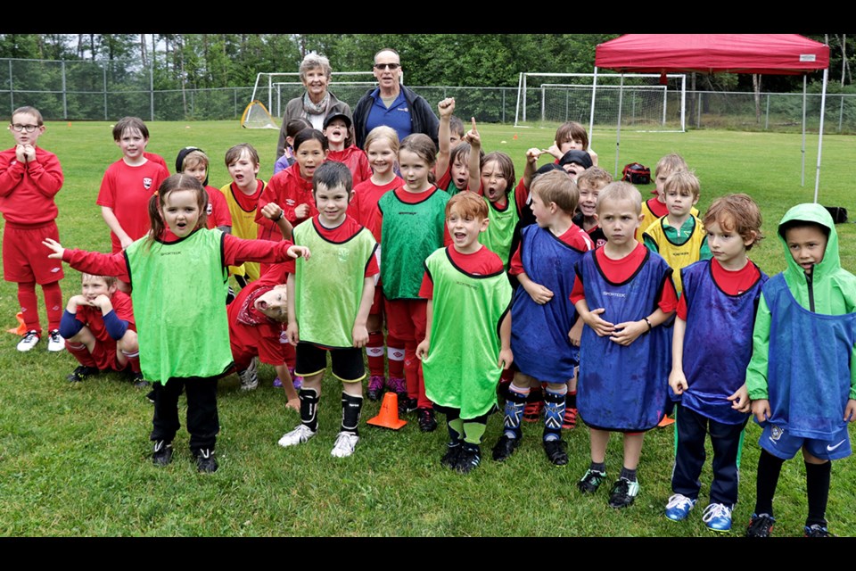 Hilary Butler (back left) and Ross Patterson (back right) of the Rotary Club join the kids for a celebratory photo. The Rotary Club donated money toward the red T-shirts all the kids are wearing.