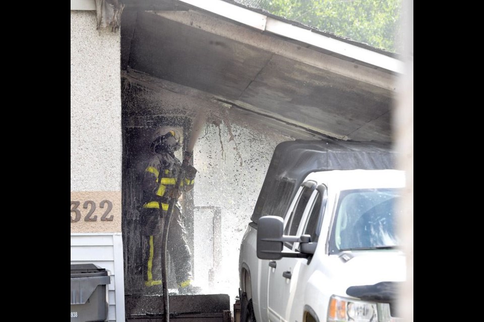 A firefighter works to extinguish a fire in the carport of a 2300-block Oak Street home on Monday morning.