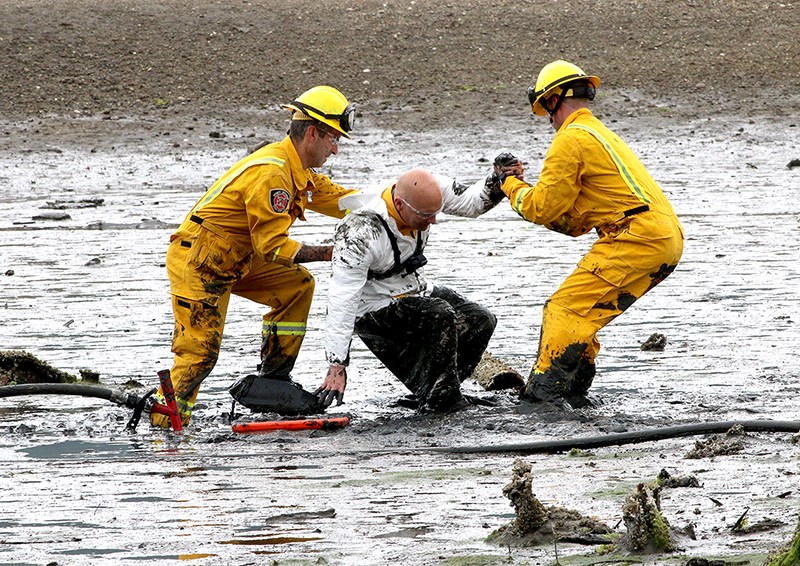 MARIO BARTEL/THE TRI-CITY NEWS
Port Moody fire caption Rob Suzukovich gets some help back on his feet from his "rescuers," firefighters Darren Penner and Jason Webster, during a training exercise to extricate people trapped in the mudflats at the east end of Port Moody Inlet.