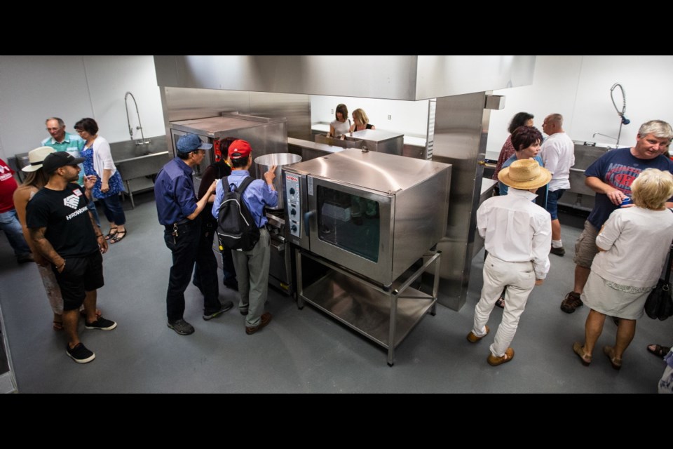 People line up at the opening of the commercial kitchen, installed by HeroWork, at the Food Rescue Distribution Centre on Saturday.