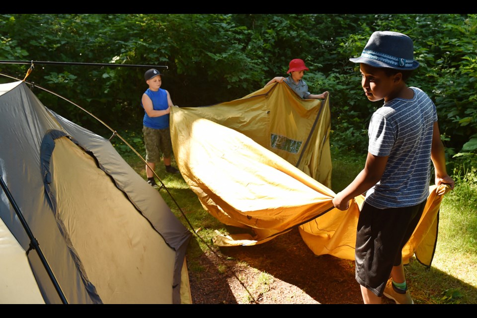 First-time camper Ami States (right), Paul Winer (middle) and Logan Hagel-Noel work on putting up their tent. Photo Dan Toulgoet