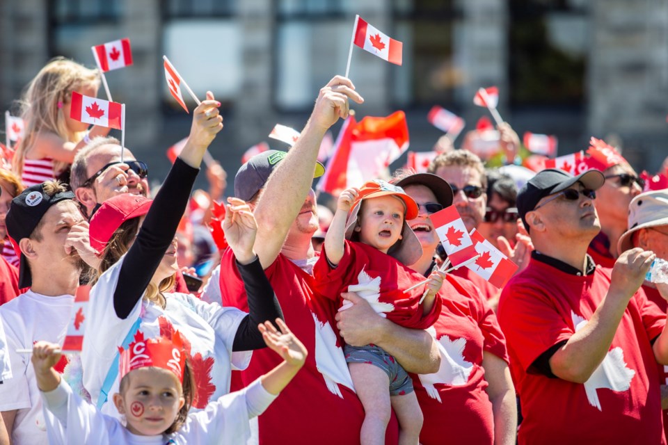People take part in the living flag on the lawn of the legislature on Canada Day
