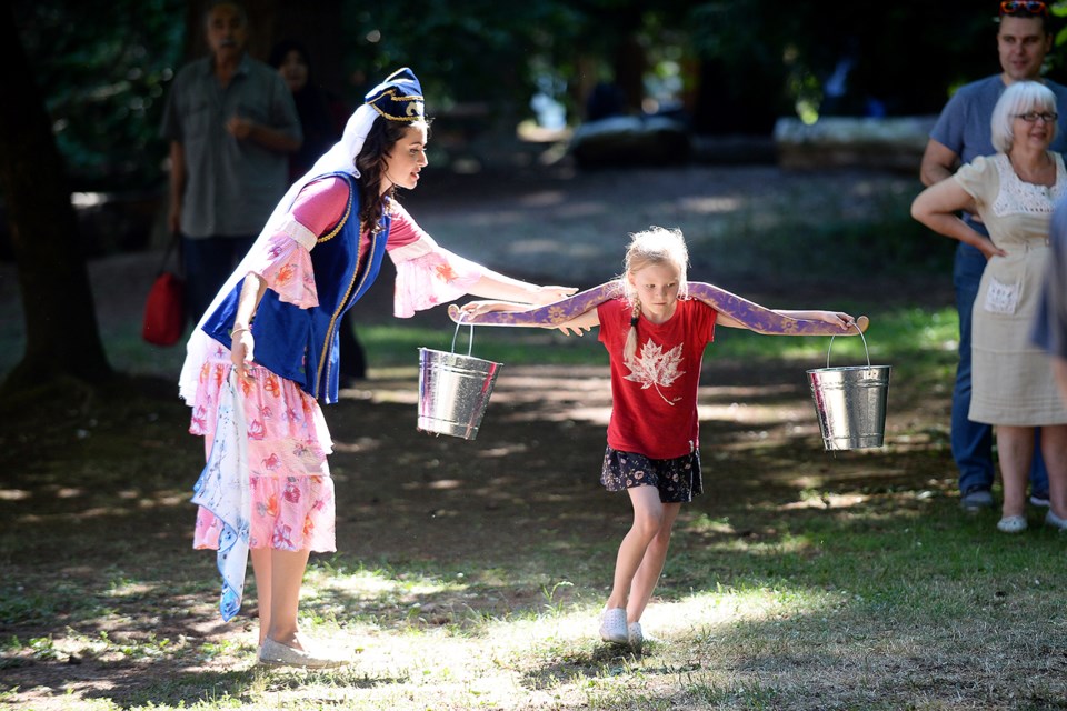 Fatima Issa, left, helps out during a game where participants try to carry water without spilling.