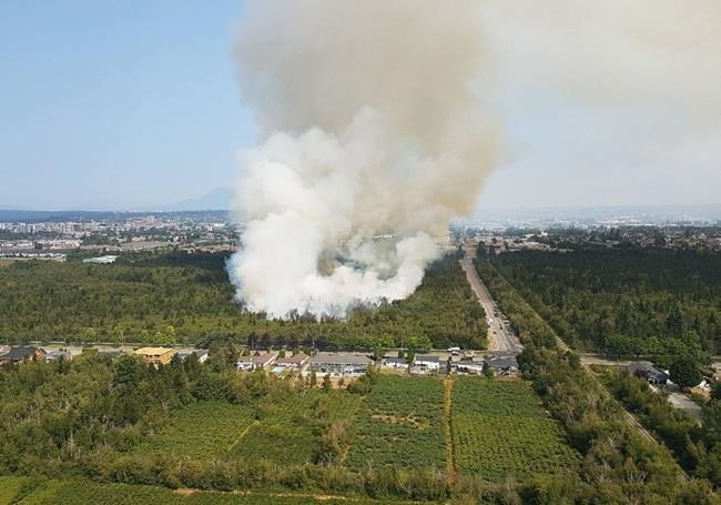 A wildfire is shown burning near the Westminster highway on Department of Defense land in Richmond, B.C. on Friday July 27, 2018. The blaze broke out around 6 a.m. in bush and forest next to the Richmond Nature Park, a bog-forest area. THE CANADIAN PRESS/HO-BC Wildfire Service *MANDATORY CREDIT *