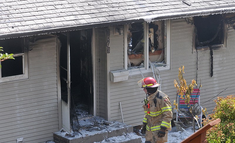 A Coquitlam firefighter surveys the damage to a home in the 3000-block of Spuraway Avenue that was gutted by fire Tuesday morning. The fire, which started at 10:50 a.m., prompted Coquitlam RCMP to evacuate several nearby homes while firefighters knocked down the flames. Spuraway was also closed between Daybreak Avenue and Ranch Park Drive.