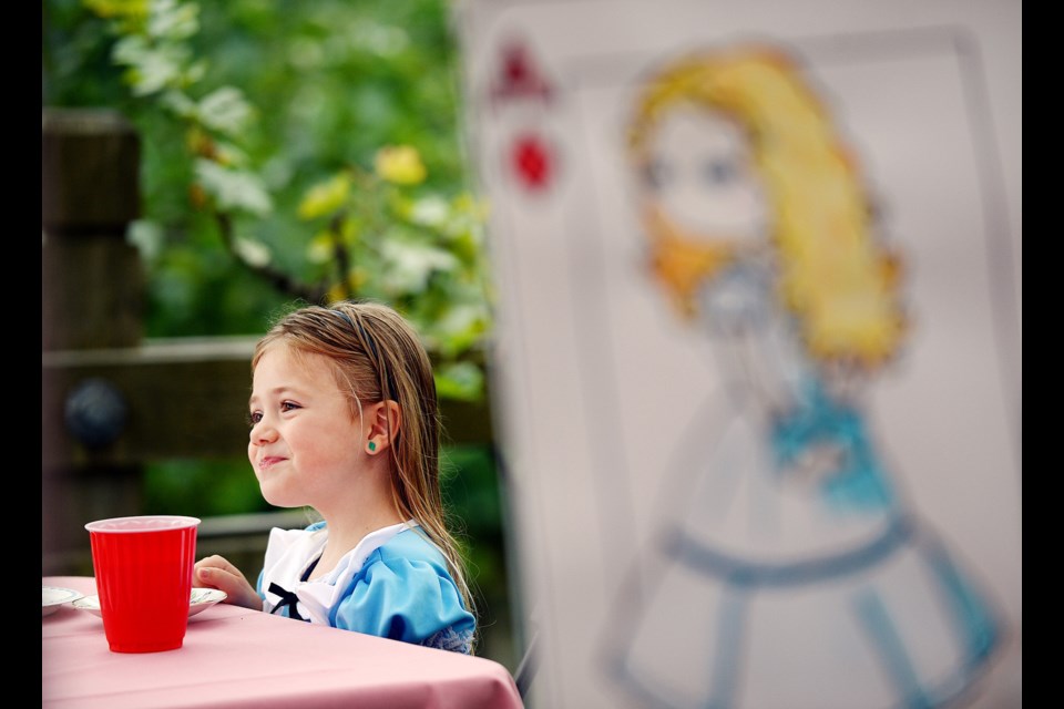 What's a Mad Hatters Tea Party without Alice? Four-year-old Alice Comer, in her Alice in Wonderland garb, finds the perfect backdrop for a photo moment.