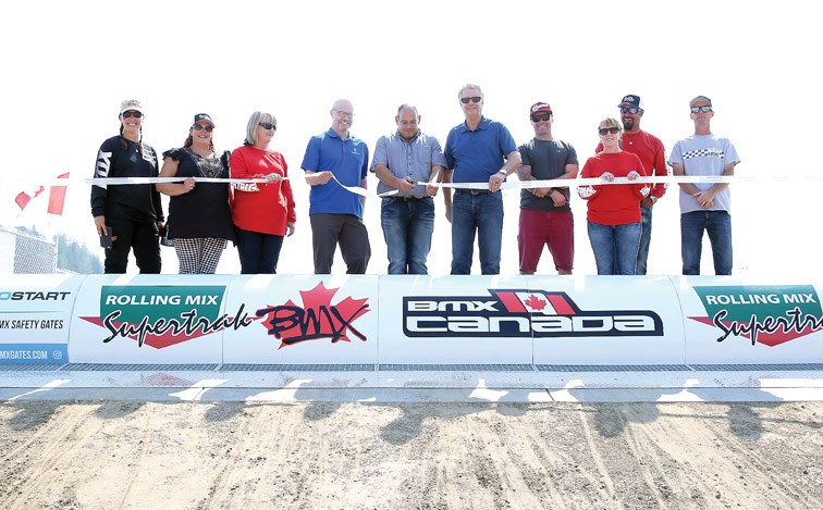 Flanked on the left by city councellor Garth Frizzell and on the right by mayor Lyn Hall, along with executive members of the Supertrak BMX Club, John Paolucci, president of Rolling Mix Concrete, cuts the ribbon to officially open the remodeled facility Saturday at Carrie Jane Gray Park.