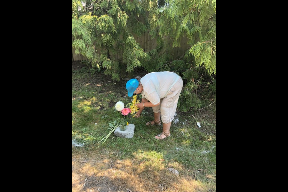 A friend of the victims' mother places flowers at crash site on Central Saanich Road.