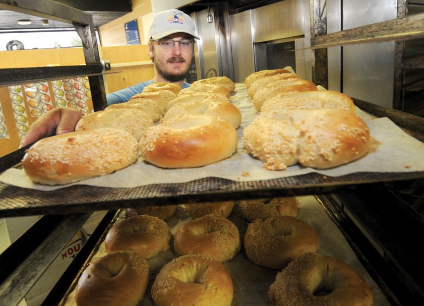 Alex Wolfsjager takes trays of bagels out of the oven at Queensbury’s Mount Royal Bagel Factory.