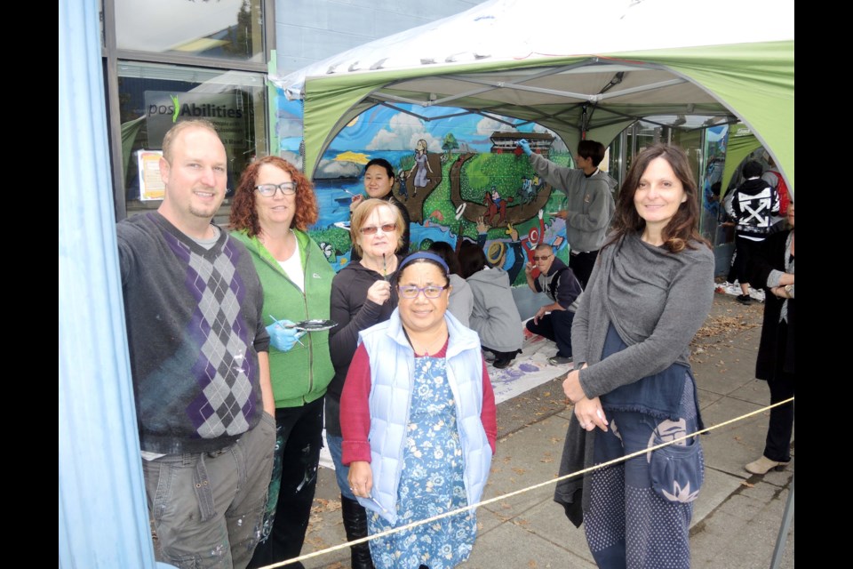 PosAbilities staff and members take a break from painting their community mural. Alan Campbell photos