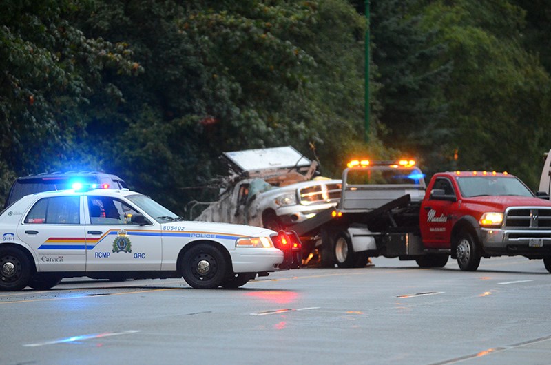 A tow truck pulls the wreckage of a pickup from the trees beside Lougheed Highway east of Lake City Way Friday morning. The driver died in a single-vehicle crash at about 1 a.m. Two passengers were taken to hospital with serious but non-life-threatening injuries.