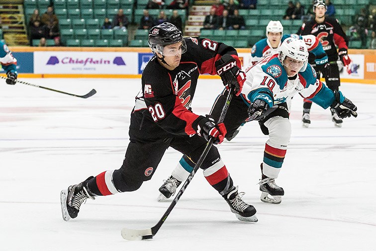 Cougars centre Ilijah Colina fires a shot on goal with Kelowna Rockets defender Ted Brennan in hot pursuit during WHL action Saturday at CN Centre. The Rockets won 5-2.