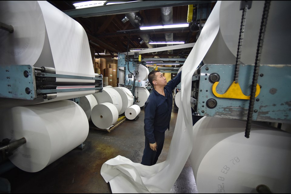 A press operator splices two rolls of paper together to keep the machines running without interruption. Photo Dan Toulgoet