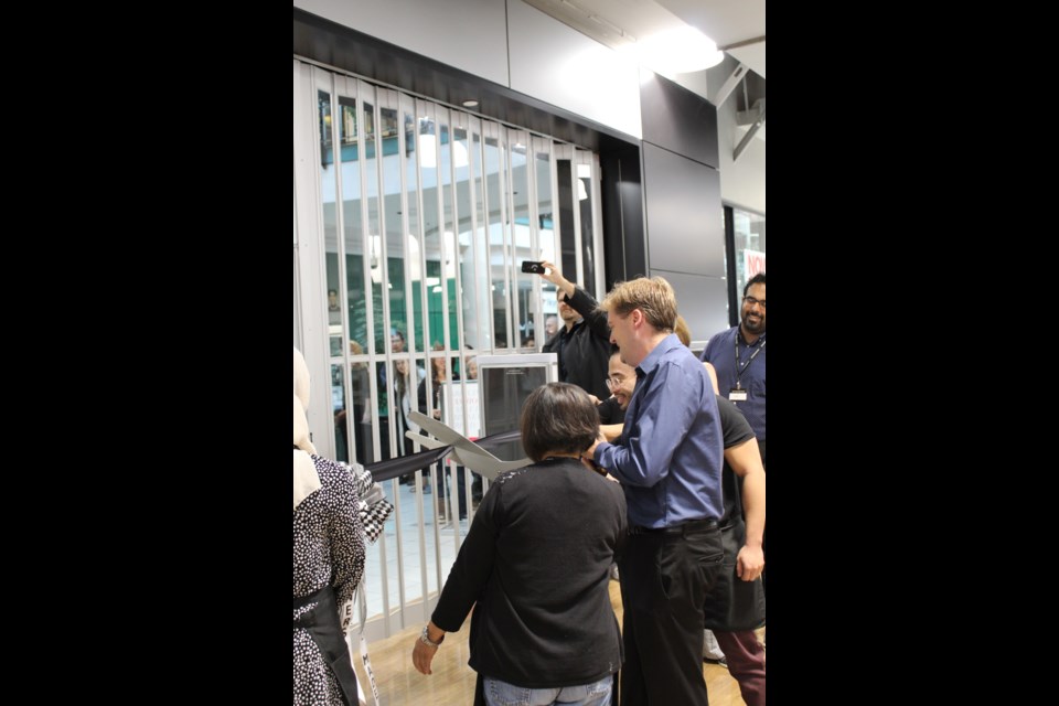 Mayor Jonathan Cote used giant scissors to help cut the ribbon as part of this week's grand opening of the new Winners store in Royal City Centre.