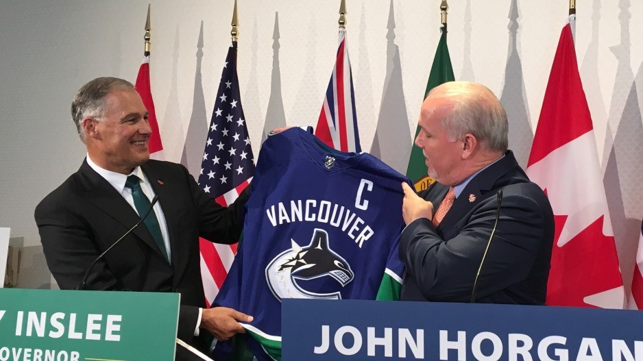 Washington state Gov. Jay Inslee accepts a Vancouver Canucks jersey from B.C. Premier John Horgan. T