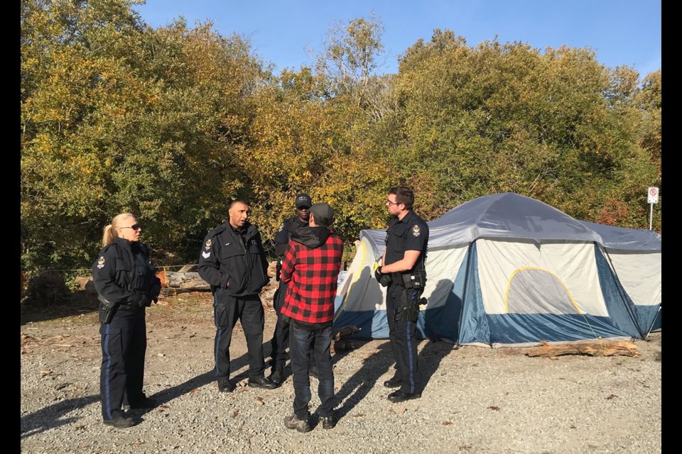 Police meet with a camper near Cattle Point on Thursday morning. Oak Bay police said Wednesday night they wanted the campers gone by 9 a.m. Camp leader Chrissy Brett said the homeless campers plan to stay about a week.