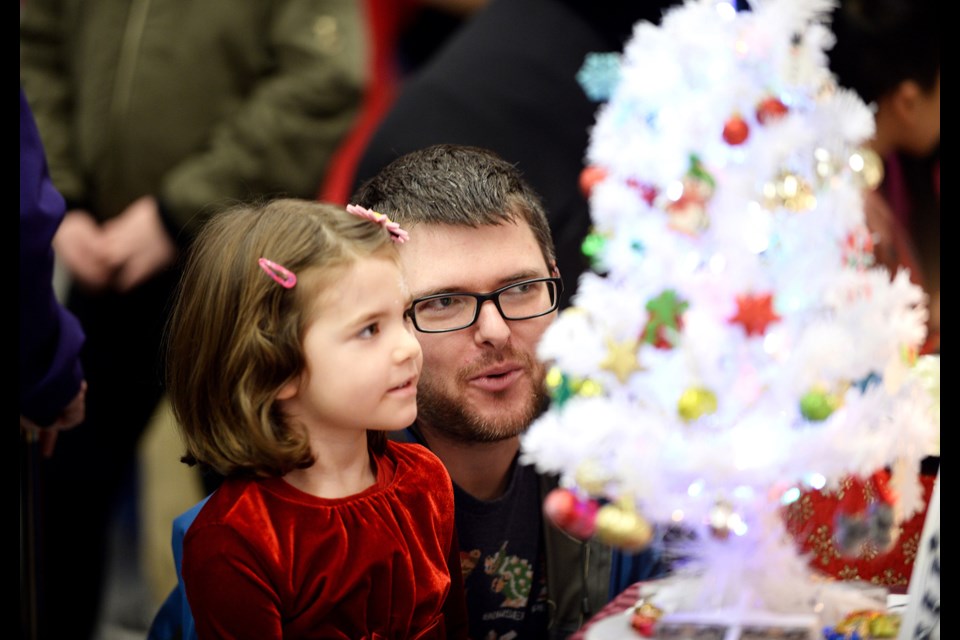 David Mosimann and three-year-old Amelia look at earrings at Brenda's Bangles and Baubles at last year's Deer Lake Craft Festival at Shadbolt Centre for the Arts. This year's event returns Nov. 16 to 18.