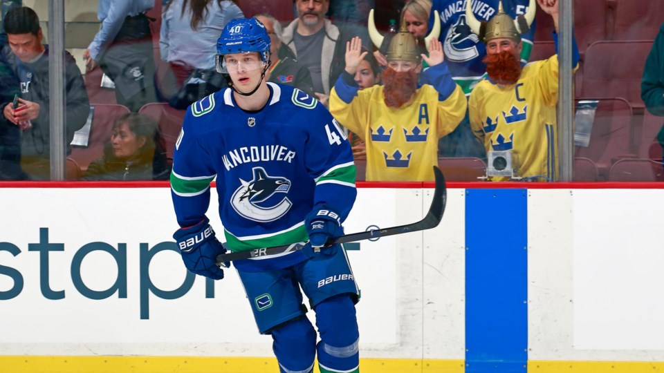 Elias Pettersson warms up with two Swedish vikings in the stands behind him.