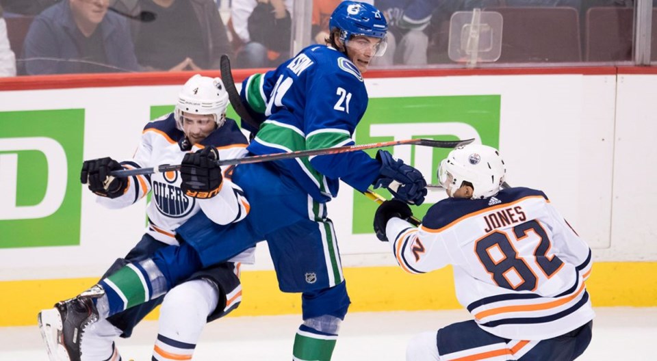 Loui Eriksson is checked by two Edmonton Oilers players