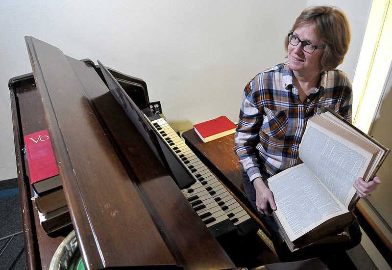 MARIO BARTEL/THE TRI-CITY NEWS
Julie Lebrun, the pastor at St. Andrews United Church in Port Moody, enjoys some last moments with the church's pipe organ and old bibles that will be amongst the items being sold at its sale on Saturday, from 9 a.m. to 3 p.m. Everything from choir robes to kitchen ware to books, furniture and the church's pews will be up for grabs as the congregation prepares to move to temporary digs at Kinsight in Port Coquitlam while the property is redeveloped into affordable housing, office space and a new 540-square metre church.