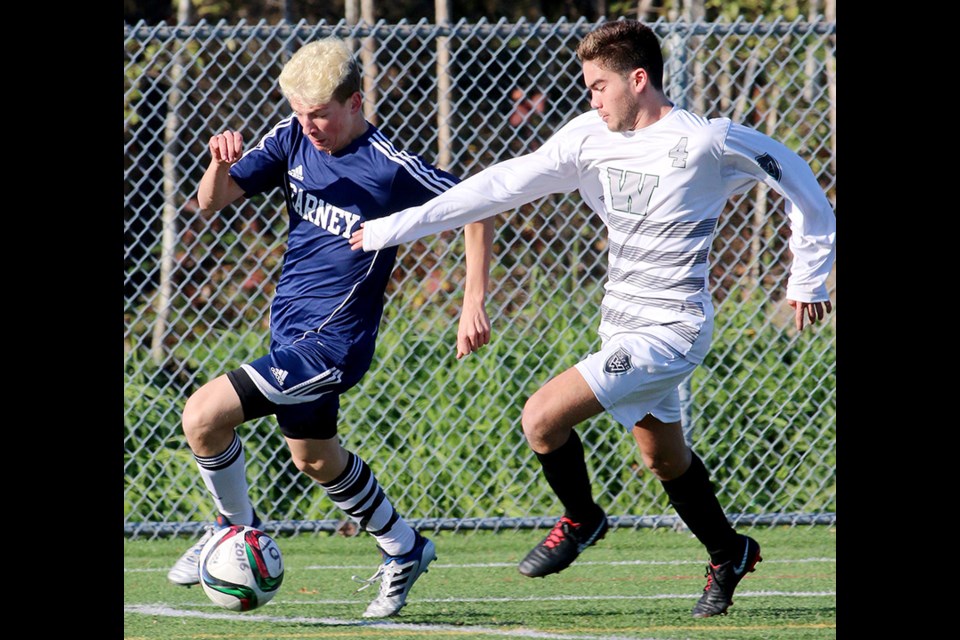 MARIO BARTEL/THE TRI-CITY NEWSArchbishop Carney forward Kaleb Vinthers tracks down a ball ahead of Windsor defender Victor Paganini in the first half of their first round match at the BC Secondary Schools Soccer Association AA provincials, Monday at the Burnaby Lake Sports Complex West.