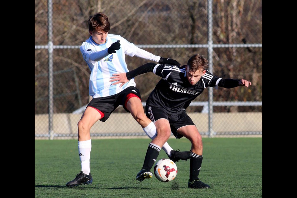 Alpha’s Lucas Dasovic, at left, battles a Thomas Haney opponent for possession during early round action at the AA provincials.