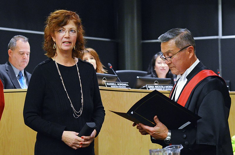 Trustee Christine Cunningham takes the oath of office with B.C. Provincial Court Judge Pedro de Couto at a public school board meeting at Burnaby Central Secondary Monday night.