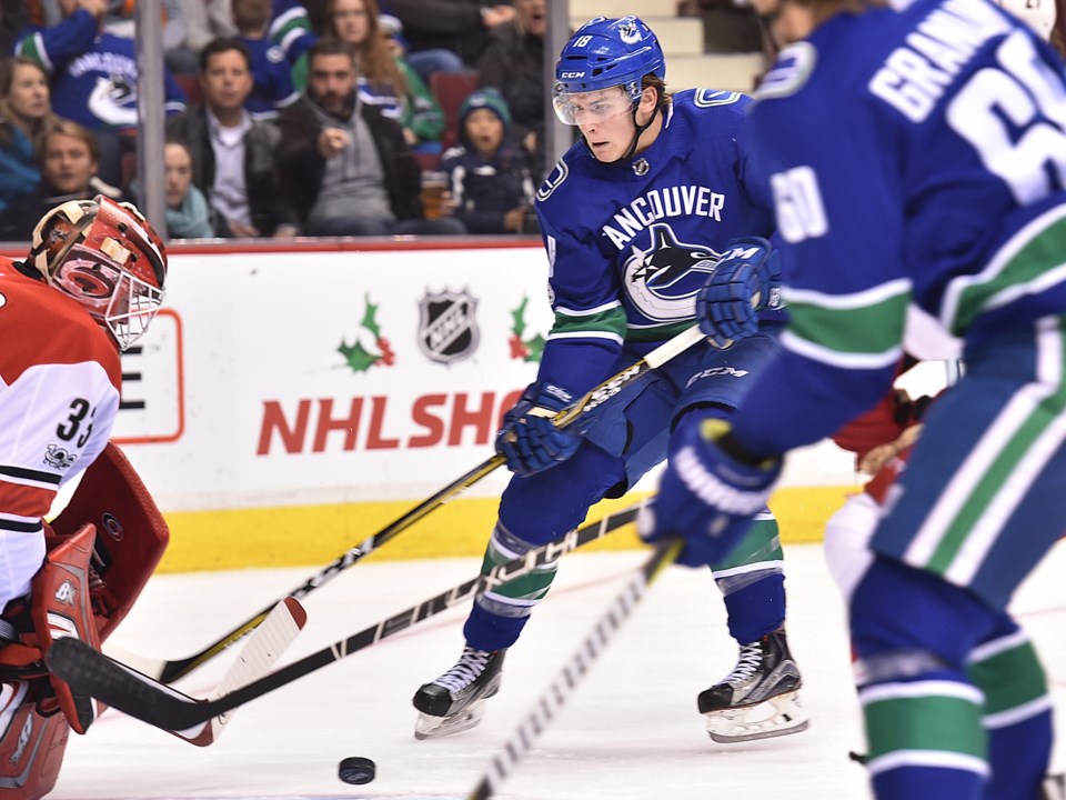 Jake Virtanen holds off a check as he carries the puck for the Vancouver Canucks.