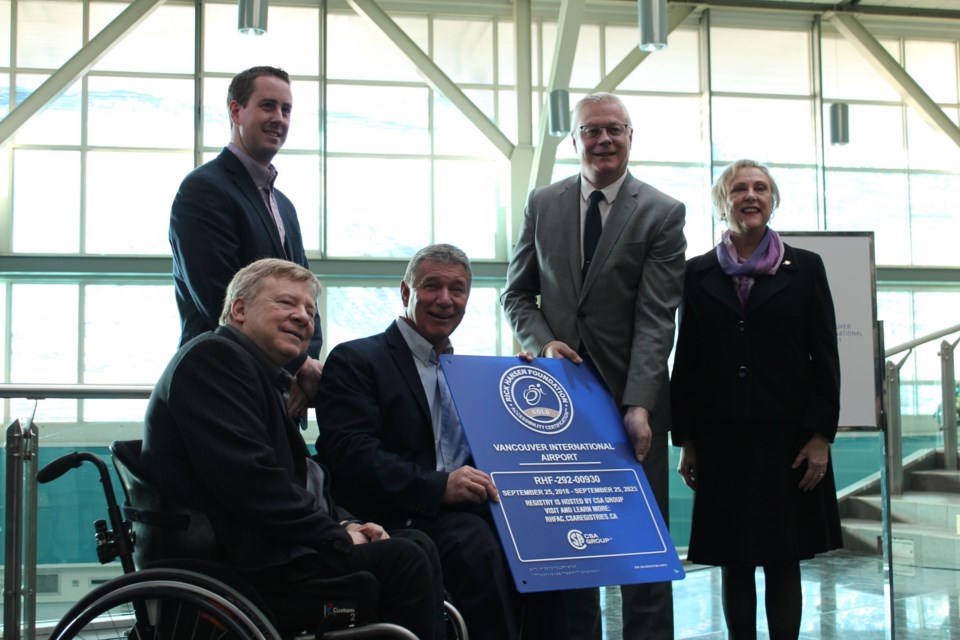 Richmond's Rick Hansen and (centre) presents YVR's Craig Richmond with a plaque recognizing its "accessibility certified gold" rating. Photo: Alyse Kotyk