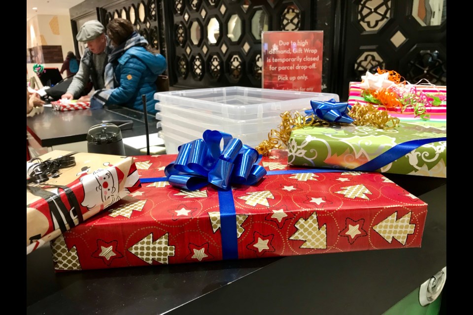 A couple gets a book wrapped at the Share gift wrapping station at Coquitlam Centre mall on Monday afternoon.